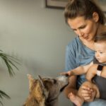 Una madre tiene in braccio un bambino mentre un cane si avvicina curioso.